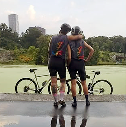 Two cyclists in Hummingbird Fuels tshirts standing by their bicycles.