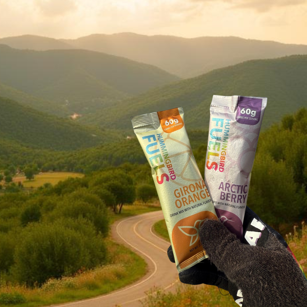 Two Hummingbird Fuels single serves held in front of a scenic mountain landscape