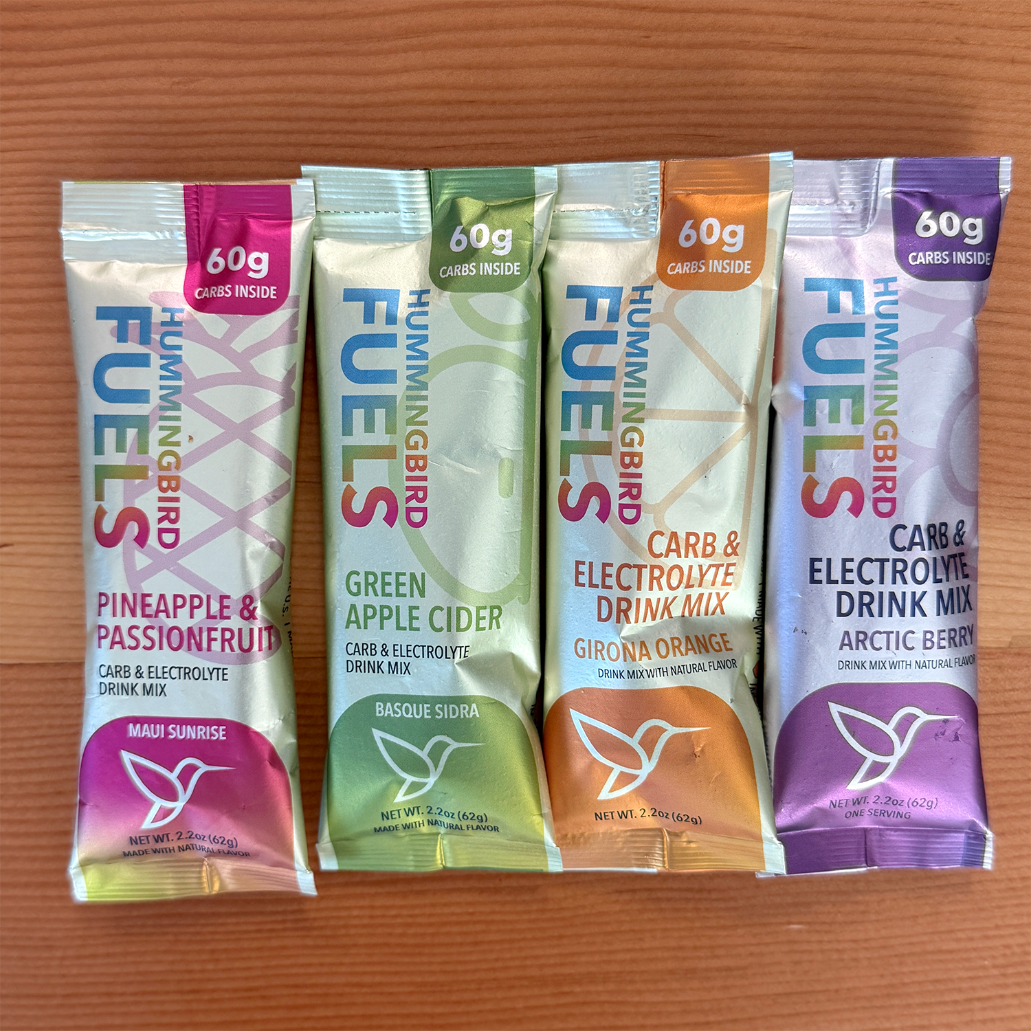 Four Hummingbird Fuels drink mix packets on a wooden surface