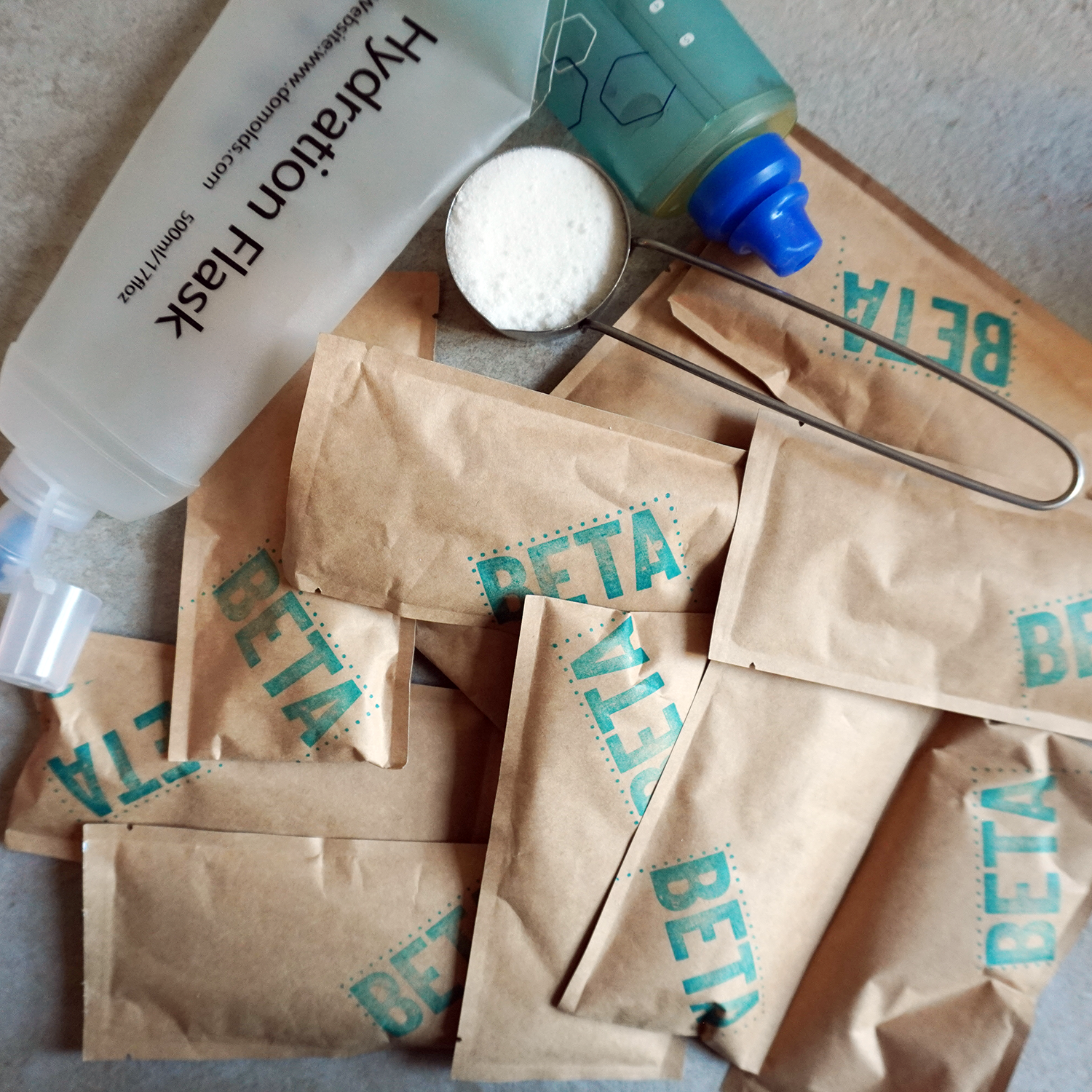 Hummingbird Fuels Magic Gel BETA packets with a scoop and container on a textured surface